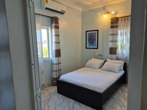 a bedroom with a bed with white sheets and a window at Appartement moderne avec balcon in Lomé