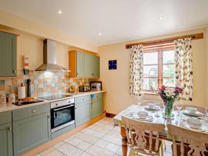 a kitchen with green cabinets and a table with chairs at 3 Bed in Langport oc-76372 in Drayton