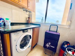 a kitchen with a washing machine and a window at City center with amazing sea view in Torre del Mar