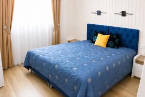 a blue bed with a blue comforter and yellow pillow at Aukštupio Vila in Aukštupėnai