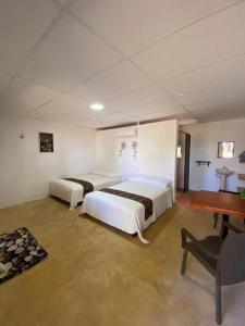 a bedroom with two beds and a table and a desk at Hotel Shalva Barahona in Izamal