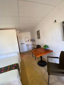 a room with two beds and a wooden table at Hotel Shalva Barahona in Izamal