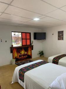 a room with two beds and a fire place at Hotel Shalva Barahona in Izamal