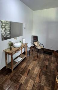 a bathroom with a sink and a chair in a room at Pousada chafariz in Pirenópolis