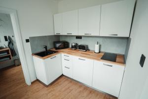 a kitchen with white cabinets and a wooden counter top at Apartmány u Jeníka in Děčín