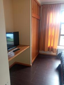 a living room with a tv and a tv stand with a television at Cabañas Lago Sur in Puerto Varas