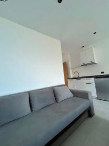 a couch in a living room with a kitchen at Borsh sunset apartments in Borsh +62 photos