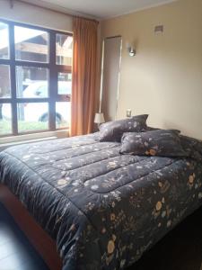 a bedroom with a bed and a large window at Cabañas Lago Sur in Puerto Varas