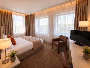 a hotel room with a bed and a flat screen tv at guestified GRAND AIRPORT Hotel Düsseldorf Ratingen in Ratingen +56 photos