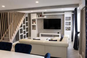 a living room with a white couch and a tv at Apartament Deluxe Bistrita in Bistriţa