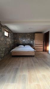 a bedroom with a bed and a stone wall at Mini Garden PREMIUM in Mojkovac