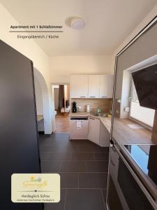 a kitchen with white cabinets and a tile floor at Heideglück Soltau - Ferienwohnungen An der Weide in Soltau
