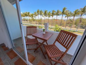 two chairs and a table on a balcony with palm trees at Lofts Terra Nuevo Vallarta in Nuevo Vallarta