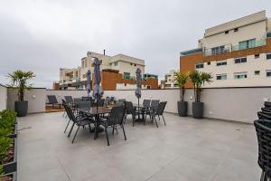 a patio with tables and chairs on a rooftop at Cabral Smart Comfort in Curitiba