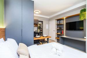 a bedroom with a bed and a desk with a television at Cabral Smart Comfort in Curitiba