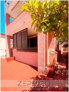 a pink building with a window and a tree at Zephiro Guest House in La Maddalena