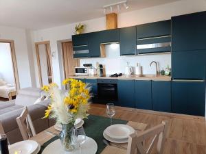 a kitchen with blue cabinets and a table with flowers on it at Apartamenty Kaniówka 25 in Gliczarów Górny