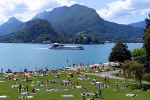 a group of people sitting on the grass near a lake at Le Lac Bleu - Sevrier in Sévrier