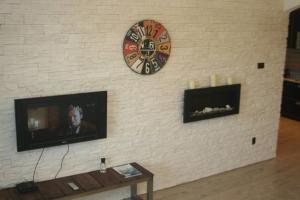 a wall with a clock and a television on it at Apartment Argentinská 8 in Prague