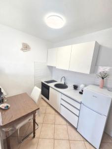 a kitchen with white cabinets and a wooden table at Apartments Mate in Komiža +20 photos