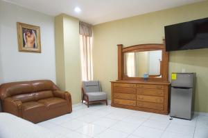ein Schlafzimmer mit einem Stuhl, einer Kommode und einem Fernseher in der Unterkunft Hotel Real Alteño in Tepatitlán