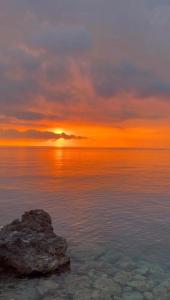 a sunset over the ocean with a rock in the water at Dimora di Diamante in Diamante