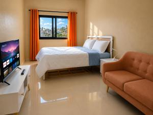 a bedroom with a bed and a tv and a couch at Milestone City Business Apartment - Secure Area - Fast WiFi Long Stay in Antananarivo