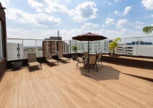 a balcony with a table and chairs and an umbrella at Tulip Inn Bauru in Bauru
