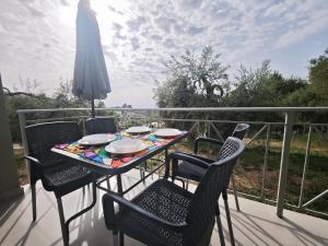 a table with chairs and an umbrella on a balcony at Μπαλκόνι με Θέα in Pérdika