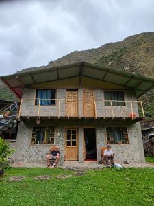 two people sitting in front of a house at Salkantay Wasi in Colcapampa