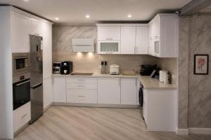 a white kitchen with white cabinets and appliances at Apartament Deluxe Bistrita in Bistriţa