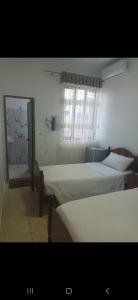 a bedroom with two beds and a mirror in it at Vila Ameli Bucimas in Buçimas