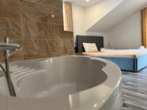 eine weiße Badewanne in einem Zimmer mit einem Bett in der Unterkunft ASADOR Hotel & Restaurant GmbH in Netphen