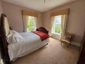 a bedroom with a large bed and two windows at Dernacally House and Spa in Carrigans