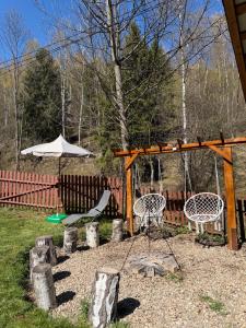a playground with two chairs and an umbrella at Căsuța din vale in Râșca +16 photos