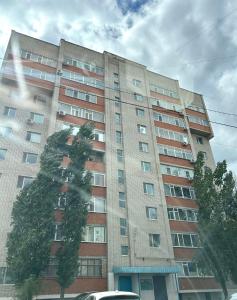 a large building with a tree on the side of it at Minimalist 2-room Apartment in Aktobe