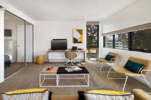 a living room with a couch and chairs and a tv at Quest Macquarie Park in Sydney