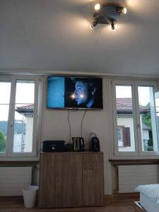 a television in a living room with windows at Zimmer mit Bad in Bühler