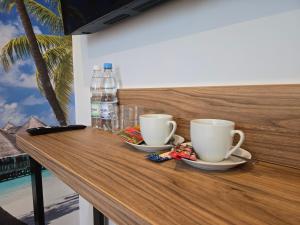 zwei Kaffeetassen auf einer Holztheke mit Wasserflaschen in der Unterkunft VUELO - shuttle gratis in Pyrzowice