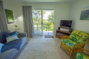 ロード・ハウにあるWaimarie Apartmentsのリビングルーム(ソファ、椅子、テレビ付)