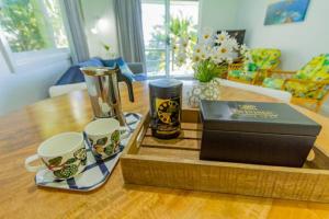 a wooden table with two coffee cups and a box at Waimarie Apartments in Lord Howe