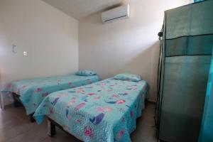 a room with two beds and a refrigerator at Escape Turquesa in Los Algodones