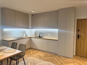 a kitchen with white cabinets and a table and chairs at Pino SeaView II in Gdańsk