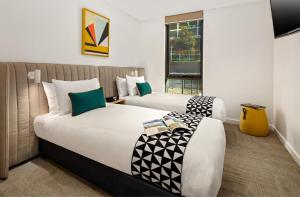 a bed room with a white bedspread and pillows at Quest Macquarie Park in Sydney