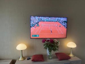 a tv hanging on a wall with a tennis match at Splendide, FACE MER avec place de parking PRIVEE in Berck-sur-Mer