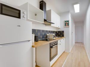 a kitchen with white cabinets and a wooden floor at Vue sur Paris, Centre Ville in Choisy-le-Roi