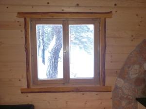 a window in a log cabin with snow outside at AJVA Chalet in Žabljak