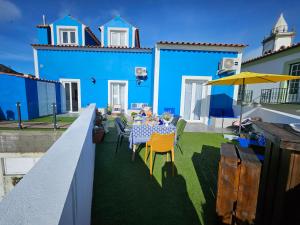 a blue house with a table and chairs and an umbrella at Farol Guesthouse in Angra do Heroísmo