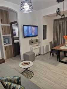 a living room with a table and a tv on the wall at Flaburiotis House in Dhriopís