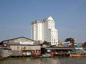 ein hohes weißes Gebäude neben einem Fluss mit Gebäuden in der Unterkunft West Hotel in Cần Thơ